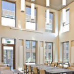 A modern restaurant full of windows and round pendant lights.